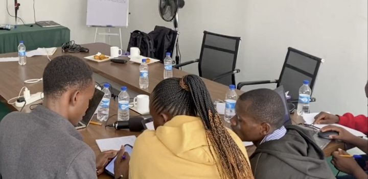 A small group of participants at the Kenyan TeacherMatic pilot collaborate during a breakout session, reviewing notes and using the toolkit on digital devices.